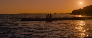 Movie still from “No Limit” (2022), directed by David M. Rosenthal – Two people are sitting on a pier in the water; Extreme Wide shot, High angle