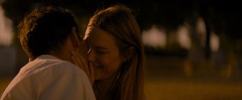 Movie still from “No Limit” (2022), directed by David M. Rosenthal – A young woman is smiling while holding a man's ear; Close Up shot, Over the shoulder angle