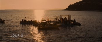 Movie still from “No Limit” (2022), directed by David M. Rosenthal – A group of people standing on a dock next to a body of water; Extreme Wide shot, High angle