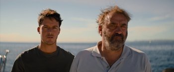 Movie still from “No Limit” (2022), directed by David M. Rosenthal – Two men standing next to each other near the ocean; Close Up shot, Low angle