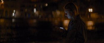 Movie still from “No Limit” (2022), directed by David M. Rosenthal – A woman looking at her cell phone in the dark; Medium shot, Low angle