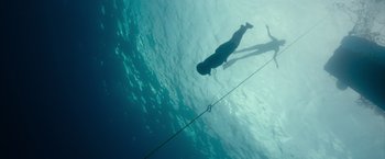 Movie still from “No Limit” (2022), directed by David M. Rosenthal – A man swimming in a body of water; Extreme Wide shot, Overhead angle