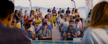 Movie still from “No Limit” (2022), directed by David M. Rosenthal – A group of people sitting on chairs on the beach; Wide shot, High angle