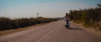 Movie still from “No Limit” (2022), directed by David M. Rosenthal – A person riding a motorcycle down the middle of a road; Wide shot, High angle