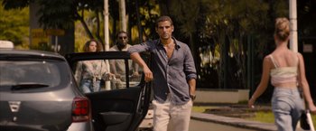Movie still from “No Limit” (2022), directed by David M. Rosenthal – A man standing next to a car on the side of the road; Wide shot, Low angle