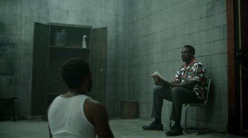 Movie still from “Atlanta” (2016), created by Donald Glover – A man sitting on a chair holding a nintendo wii game controller; Wide shot, Over the shoulder angle