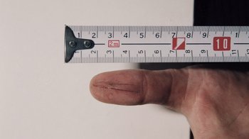 Movie still from “No Mercy, No Remorse” (2022), directed by Terry Carlyon – A person's hand and a measuring tape; Extreme Close Up shot, High angle