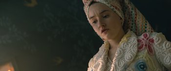 Movie still from “No One Will Save You” (2023), directed by Brian Duffield – A woman with a head scarf is looking down; Close Up shot, Over the shoulder angle