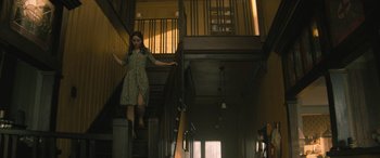 Movie still from “No One Will Save You” (2023), directed by Brian Duffield – A woman is walking down the stairs of a house; Wide shot, Low angle