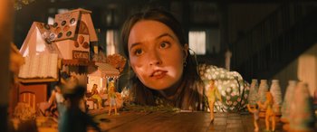 Movie still from “No One Will Save You” (2023), directed by Brian Duffield – A woman is looking over a table with a small doll; Close Up shot, Over the shoulder angle