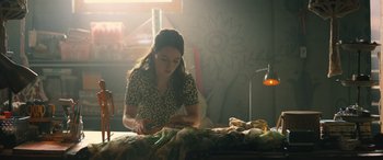 Movie still from “No One Will Save You” (2023), directed by Brian Duffield – A woman sitting at a table sewing a dress; Medium shot, Low angle