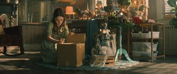 Movie still from “No One Will Save You” (2023), directed by Brian Duffield – A woman sitting on the floor next to a cardboard box; Medium shot, High angle