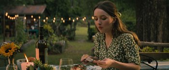 Movie still from “No One Will Save You” (2023), directed by Brian Duffield – A woman sitting at a table with a plate of food in front of her; Medium shot, Over the shoulder angle