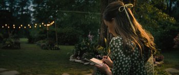 Movie still from “No One Will Save You” (2023), directed by Brian Duffield – A woman writing on a piece of paper in a park; Medium shot, Over the shoulder angle