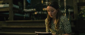 Movie still from “No One Will Save You” (2023), directed by Brian Duffield – A woman sitting on a bench reading a book; Medium shot, Over the shoulder angle