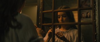 Movie still from “No One Will Save You” (2023), directed by Brian Duffield – A woman looking through a window in a room; Close Up shot, Over the shoulder angle
