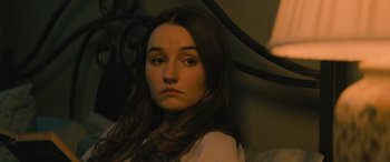 Movie still from “No One Will Save You” (2023), directed by Brian Duffield – A woman sitting on top of a bed in a room; Close Up shot, Over the shoulder angle