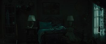 Movie still from “No One Will Save You” (2023), directed by Brian Duffield – A person sleeping on a bed in a dark room; Wide shot, High angle