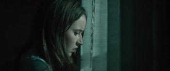 Movie still from “No One Will Save You” (2023), directed by Brian Duffield – A young woman is looking out a window; Close Up shot, Low angle