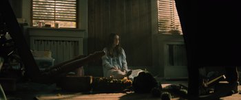Movie still from “No One Will Save You” (2023), directed by Brian Duffield – A woman sitting on the floor in front of a table; Wide shot, High angle