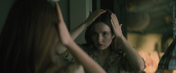 Movie still from “No One Will Save You” (2023), directed by Brian Duffield – A woman looking in the mirror while holding her hair; Close Up shot, Over the shoulder angle