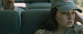 Movie still from “No One Will Save You” (2023), directed by Brian Duffield – A woman sitting in a chair wearing a hat; Close Up shot, Over the shoulder angle
