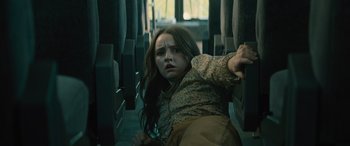Movie still from “No One Will Save You” (2023), directed by Brian Duffield – A woman is laying on the floor of a bus; Medium shot, High angle