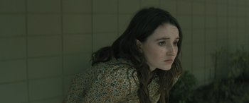 Movie still from “No One Will Save You” (2023), directed by Brian Duffield – A woman with long brown hair sitting in a room; Close Up shot, High angle