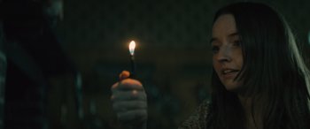 Movie still from “No One Will Save You” (2023), directed by Brian Duffield – A woman holding a lit candle in her hand; Close Up shot, High angle