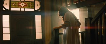 Movie still from “No One Will Save You” (2023), directed by Brian Duffield – A woman standing in front of an open door; Medium shot, Low angle