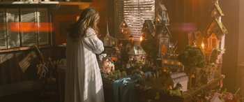 Movie still from “No One Will Save You” (2023), directed by Brian Duffield – A woman standing in front of a table with a lot of toys; Medium shot, Over the shoulder angle