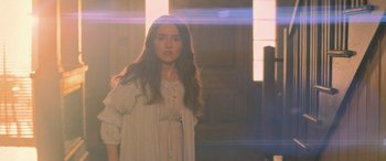 Movie still from “No One Will Save You” (2023), directed by Brian Duffield – A young woman standing in front of a window; Medium shot, Over the shoulder angle