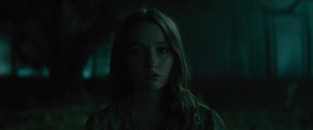 Movie still from “No One Will Save You” (2023), directed by Brian Duffield – A woman with long brown hair is in a dark room; Close Up shot, Low angle
