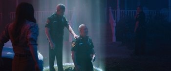 Movie still from “No One Will Save You” (2023), directed by Brian Duffield – Two police officers standing next to each other on a stage; Wide shot, High angle