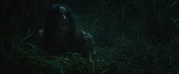 Movie still from “No One Will Save You” (2023), directed by Brian Duffield – A woman laying in the grass at night; Medium shot, High angle