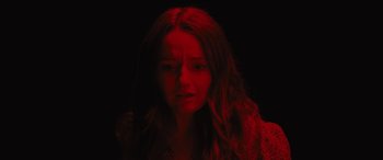 Movie still from “No One Will Save You” (2023), directed by Brian Duffield – A woman with long red hair is looking at the camera; Close Up shot, High angle