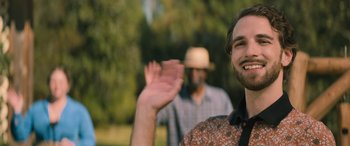 Movie still from “No One Will Save You” (2023), directed by Brian Duffield – A man waving at the camera while another man watches; Close Up shot, Over the shoulder angle