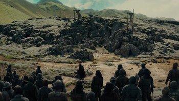 Movie still from “Noah” (2014), directed by Darren Aronofsky – A group of people sitting on top of a rock covered field; Extreme Wide shot, High angle