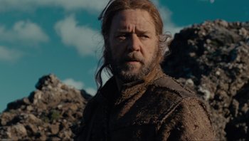 Movie still from “Noah” (2014), directed by Darren Aronofsky – A man with long hair and beard standing in a rocky area; Medium shot, Low angle