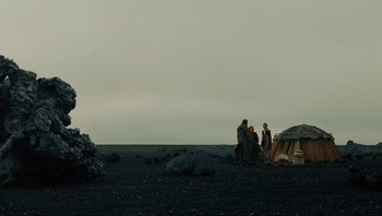 A group of people standing on top of a dirt field
