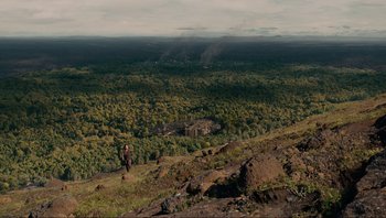Movie still from “Noah” (2014), directed by Darren Aronofsky – A person is walking on a hill with trees in the background; Extreme Wide shot, High angle
