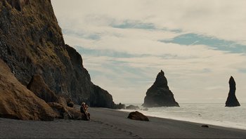 Movie still from “Noah” (2014), directed by Darren Aronofsky – Two people sitting on the beach near the ocean; Extreme Wide shot, High angle