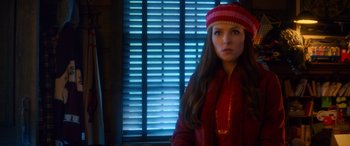 Movie still from “Noelle” (2019), directed by Marc Lawrence – A woman wearing a hat standing in front of a window; Medium shot, Over the shoulder angle
