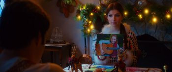 Movie still from “Noelle” (2019), directed by Marc Lawrence – A woman holding up a picture of a girl with a guitar; Close Up shot, Over the shoulder angle