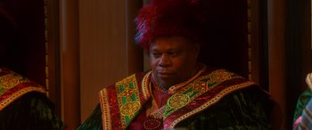 Movie still from “Noelle” (2019), directed by Marc Lawrence – A man with a red wig and a red and green outfit; Close Up shot, Over the shoulder angle