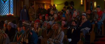 Movie still from “Noelle” (2019), directed by Marc Lawrence – A group of people sitting in front of a crowd; Medium shot, High angle