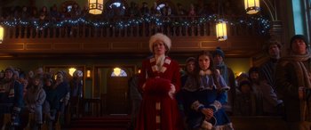 Movie still from “Noelle” (2019), directed by Marc Lawrence – A group of people standing in front of a christmas tree; Medium shot, Low angle