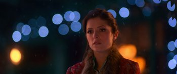 Movie still from “Noelle” (2019), directed by Marc Lawrence – A young woman wearing a fur collar and a red jacket; Close Up shot, Over the shoulder angle