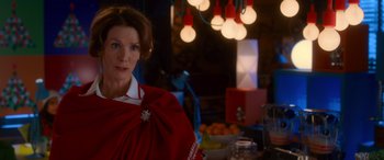 Movie still from “Noelle” (2019), directed by Marc Lawrence – A woman in a red dress standing in front of a table; Medium shot, Over the shoulder angle