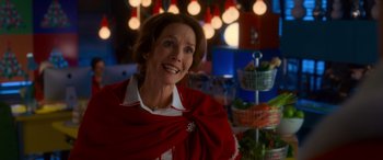 Movie still from “Noelle” (2019), directed by Marc Lawrence – An older woman wearing a red dress and a white scarf; Medium shot, Over the shoulder angle